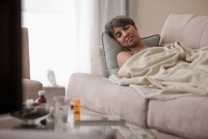 Sick mixed race woman laying on sofa