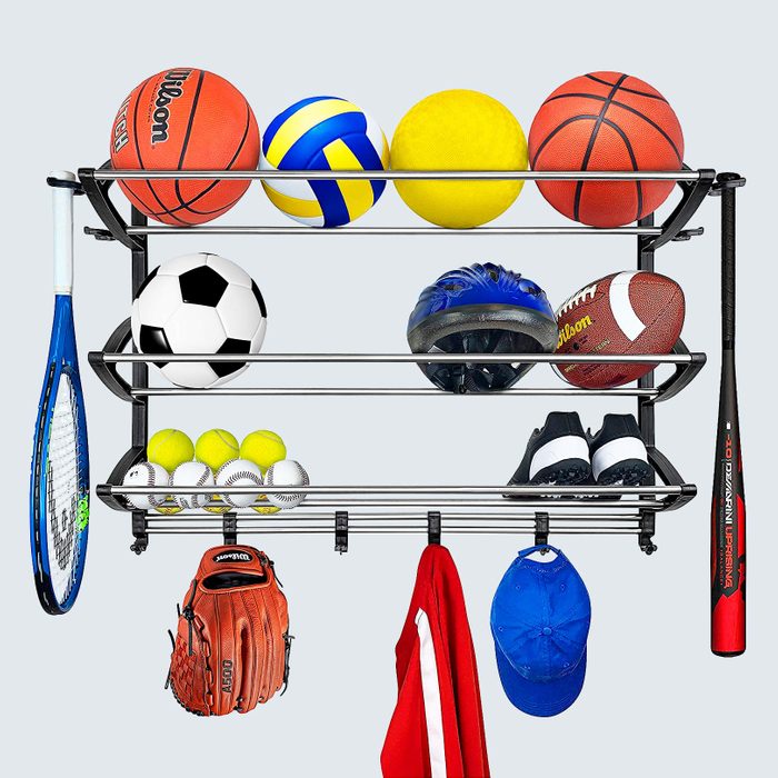 Rack holds sports equipment; basketballs, volleyball, helmet, tennis balls, shoes, bat, glove hang below. Context: plain gray background.