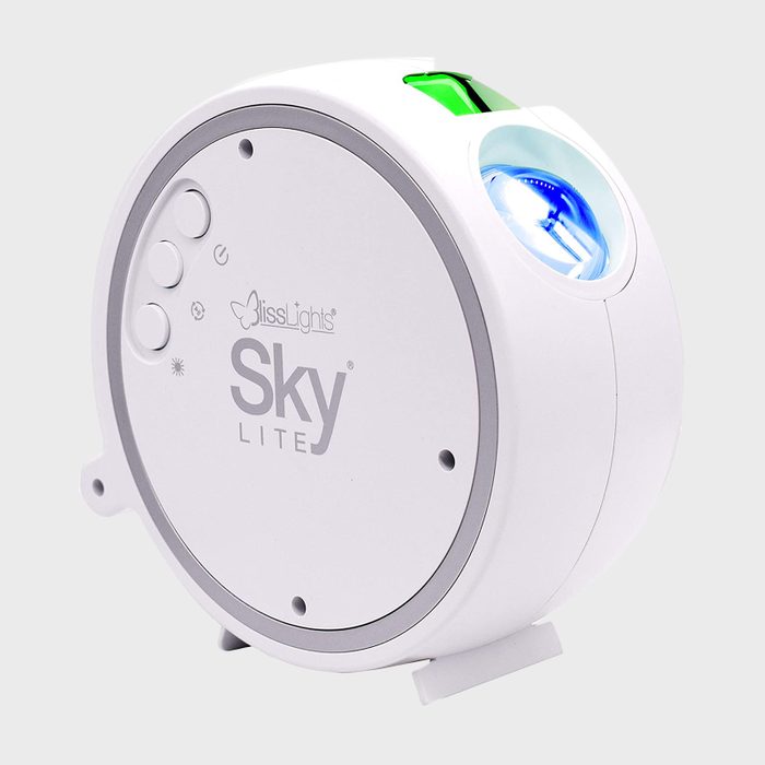 White projector with buttons, casting light, placed in a neutral setting. Text: 