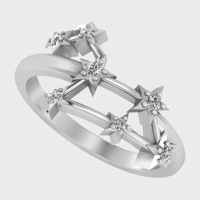 A silver ring features star-shaped settings holding small diamonds, arranged in a crisscross design against a light gray background.