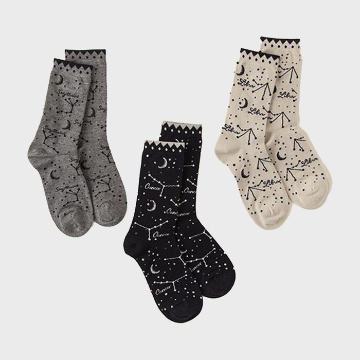 Three pairs of socks display zodiac constellations and moon patterns. Each pair, colored grey, black, and beige, features names Sagittarius, Cancer, and Libra.