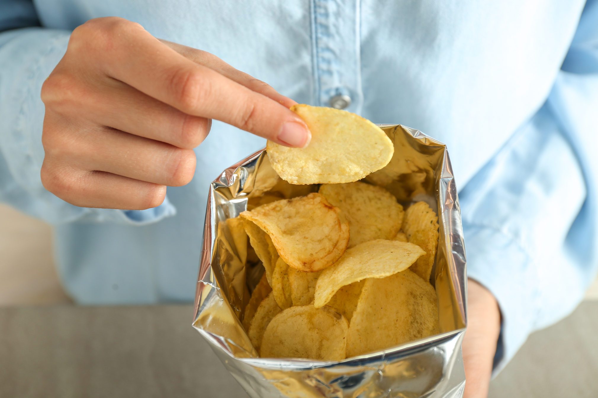 Woman eating tasty potato chips, closeup