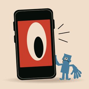 A smartphone displays a large eye on the screen, surprising a small blue cartoon figure nearby, in a minimalist setting.
