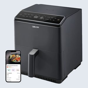 Air fryer with digital controls is displayed on a countertop; a smartphone shows a recipe app interface beside it.