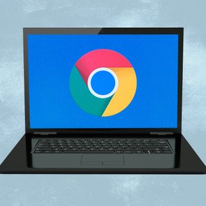 Laptop displays Chrome logo on-screen, sitting against a light blue textured background.