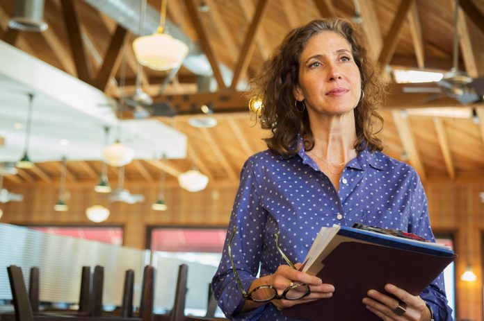 Pensive Caucasian woman holding paperwork in restaurant