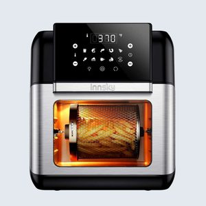 Air fryer cooking fries in a rotating mesh basket, with digital temperature display reading 