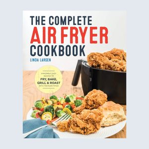 Cookbook cover features fried chicken in air fryer, accompanied by vegetables and bread on a plate. Titled 