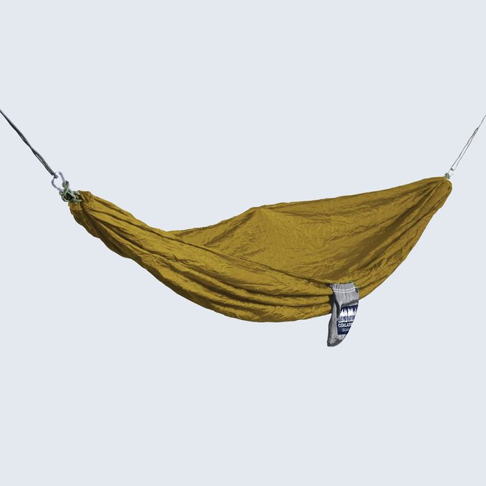 Yellow hammock hangs suspended by ropes; isolated on a pale background.