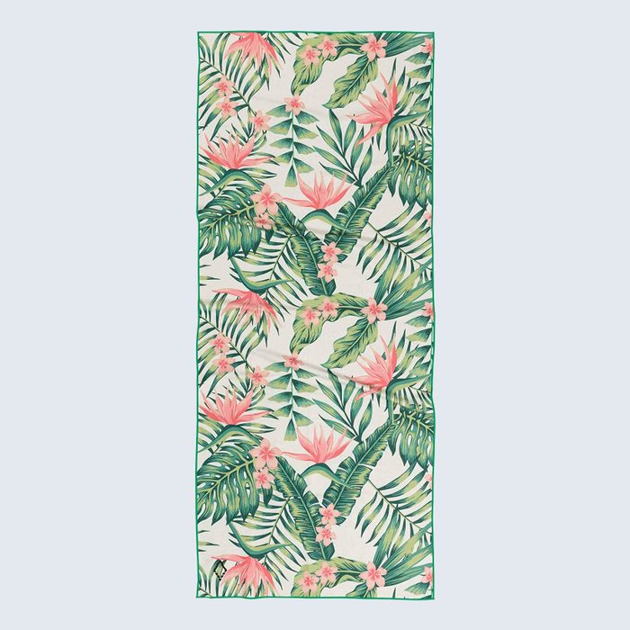 Tropical towel displaying pink flowers and green leaves, laying flat against a light background, with a bird image in one corner.