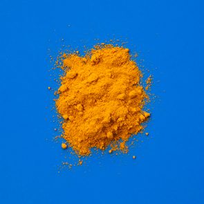 Yellow powder scattered on a bright blue surface, contrasting vividly against the backdrop.