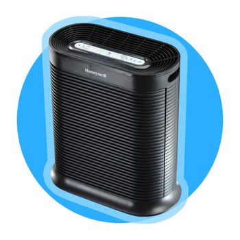 A black air purifier stands idly against a blue circular background, featuring a control panel on top with the brand "Honeywell".