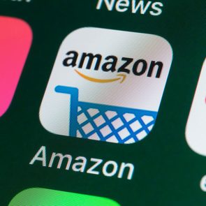 Amazon app icon showing logo above shopping cart, set against a phone screen with multiple app icons visible.