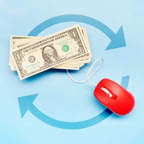 Stack of dollar bills connected by wire to red computer mouse on blue background with curved arrows.