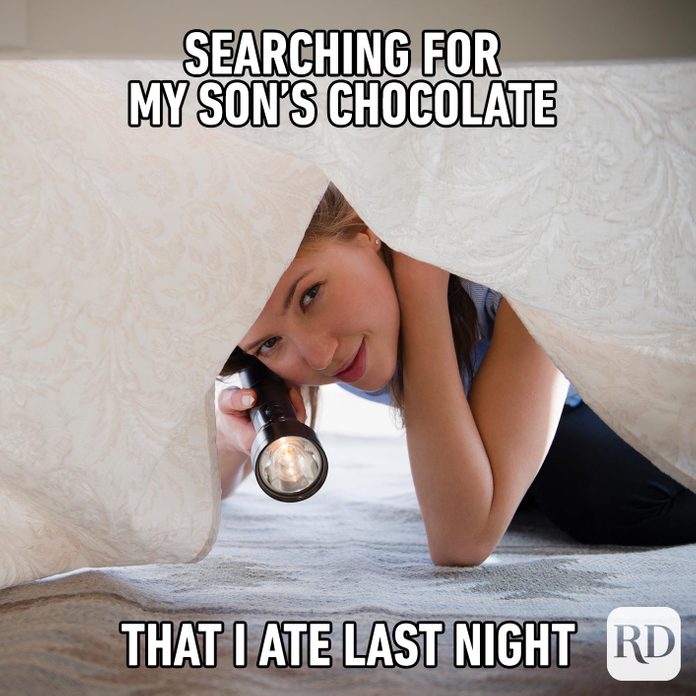 Mom smiling suspiciously as she shines a flashlight beneath bed. MEME TEXT: Searching for my son’s chocolate I ate last night