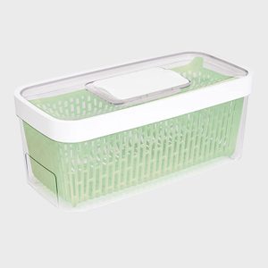A green basket sits inside a clear rectangular container with a white lid, set against a plain gray background.