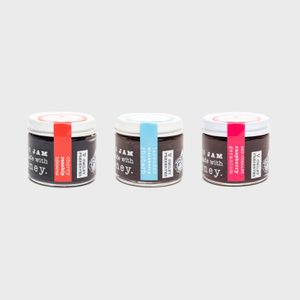 Three jars display different jams, each with colorful labels reading variety names like 