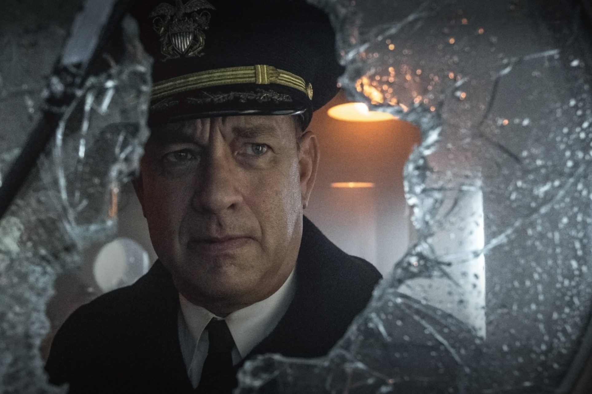 A naval officer peers through a shattered window, light softly glowing in the background, creating a tense atmosphere.