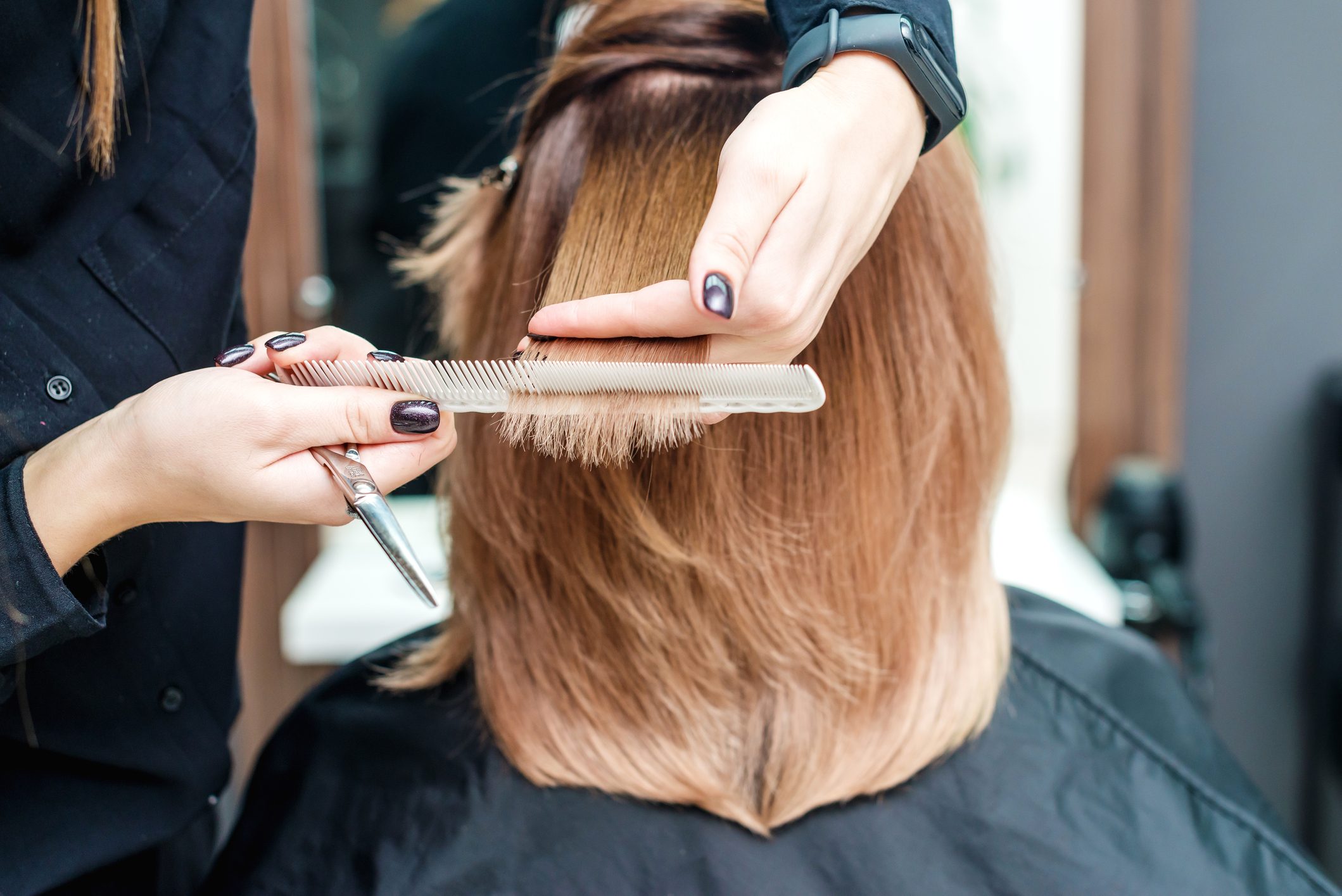 Hairdresser's hands are holding red hair in the beauty salon.