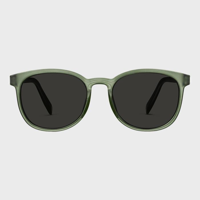Green-framed sunglasses resting on a plain gray background.