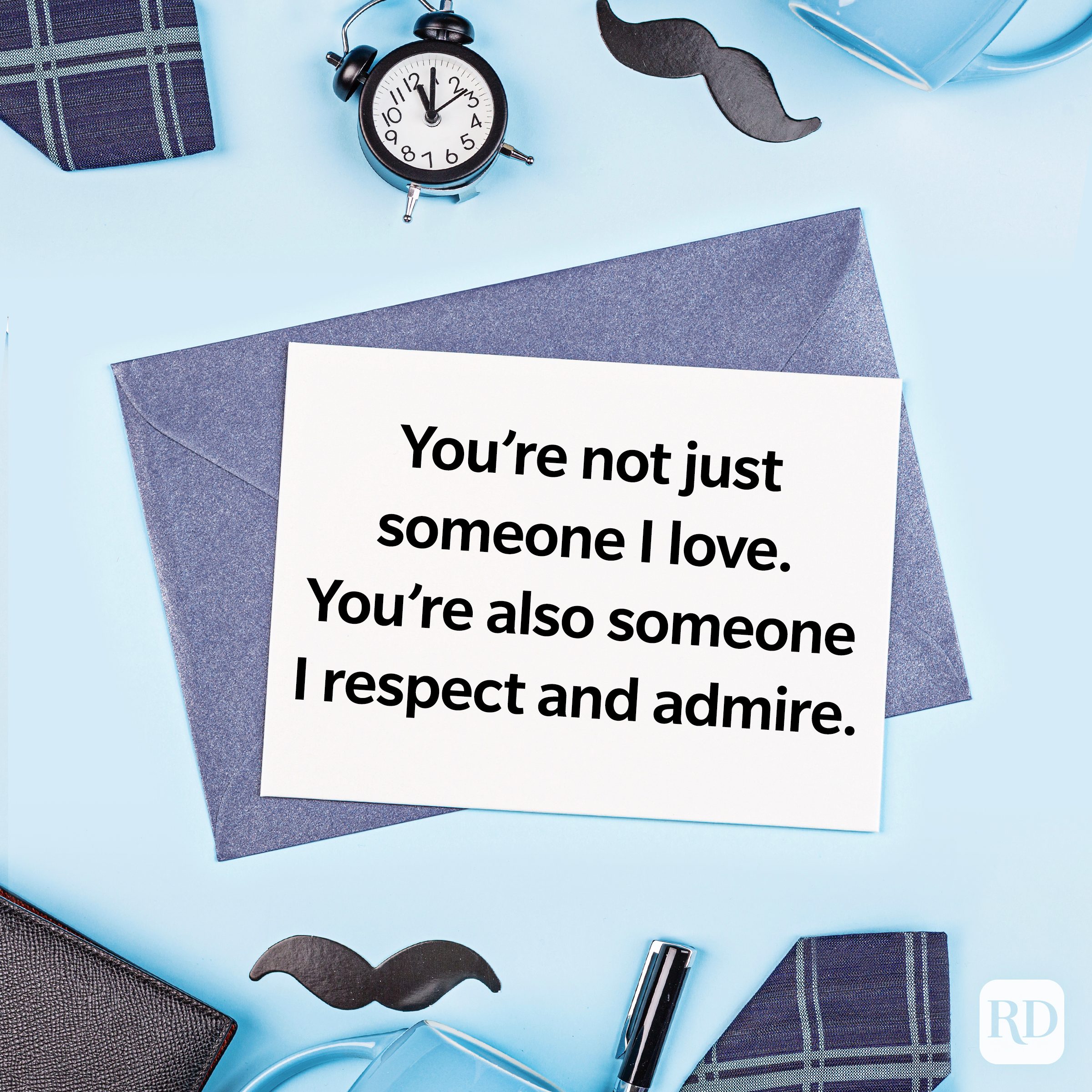 Card displays message: "You're not just someone I love. You're also someone I respect and admire." Surrounded by clock, mustache, and plaid items on blue surface.
