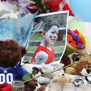 Teddy bear wearing sports jersey sits among flowers and stuffed animals; a photo of a smiling child featured prominently.