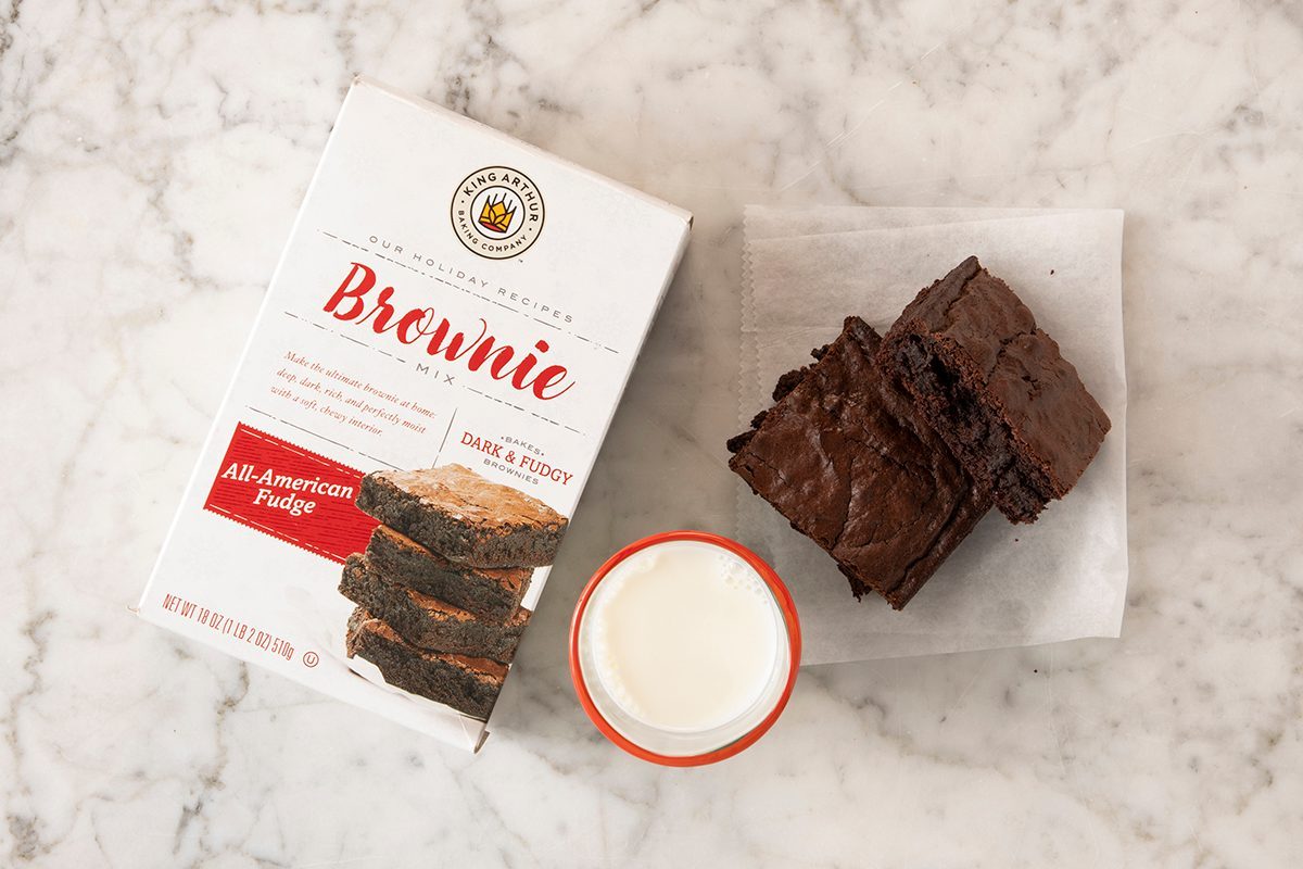 King Arthur All-American Fudge Brownie Mix in package on marble with pieces and milk