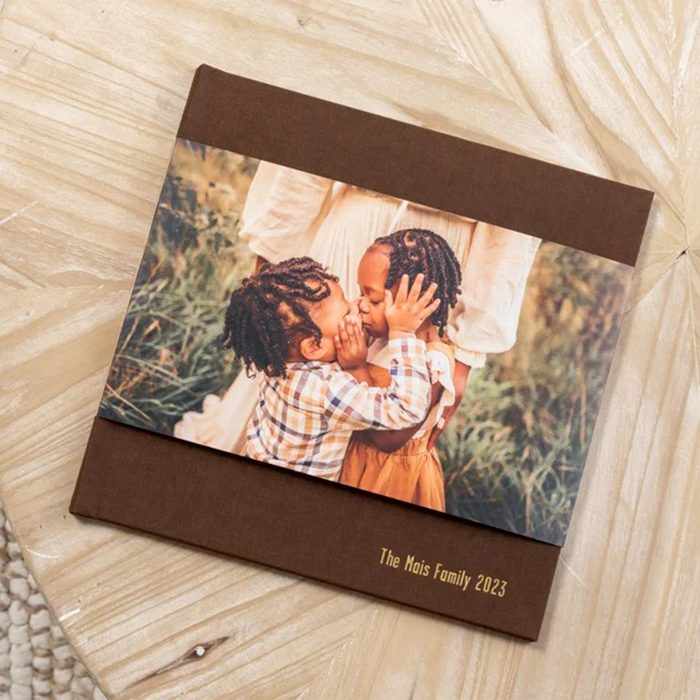 Photo book shows two children hugging, set against a nature backdrop. The cover text reads 