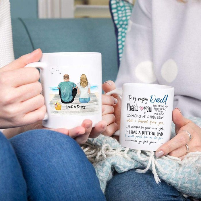 Two mugs are held by people sitting on a couch. One depicts a father and daughter at the beach; the other features a heartfelt message to 
