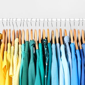Hangers display neatly organized colorful shirts, arranged in a gradient from red to purple, against a plain background.