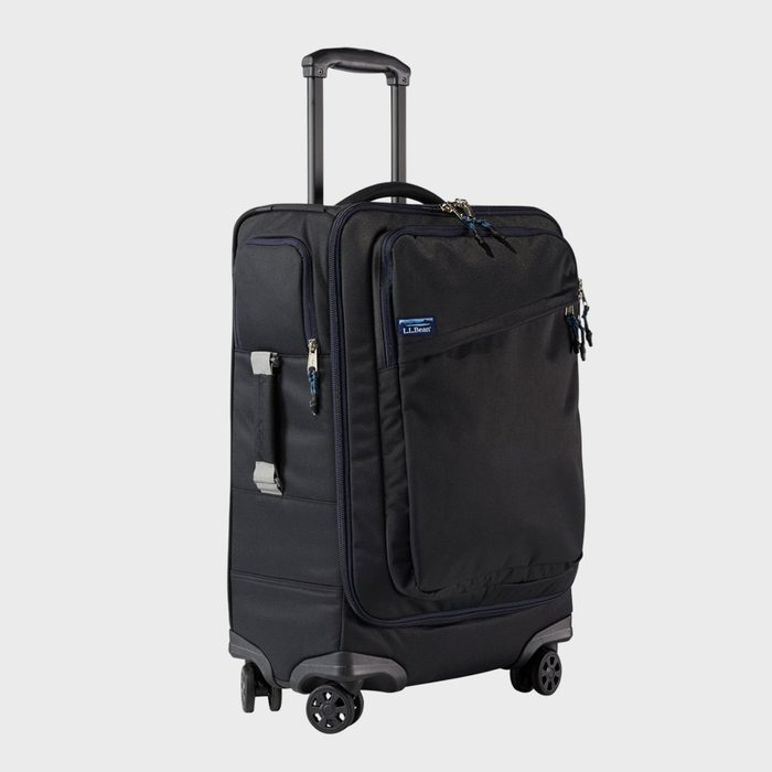 Black rolling suitcase stands upright on four wheels; retractable handle extended. The suitcase has multiple zipped compartments; labeled 