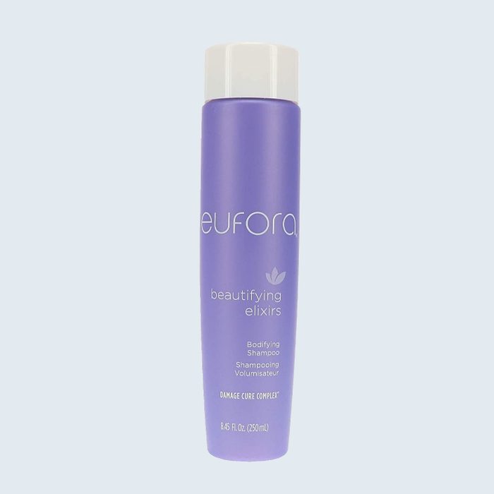 Purple shampoo bottle stands upright against plain background. Text: 