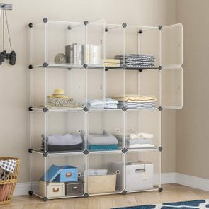 Transparent cube shelves hold folded clothes, books, and storage boxes; a woven basket sits below, and binoculars hang nearby on a wall.