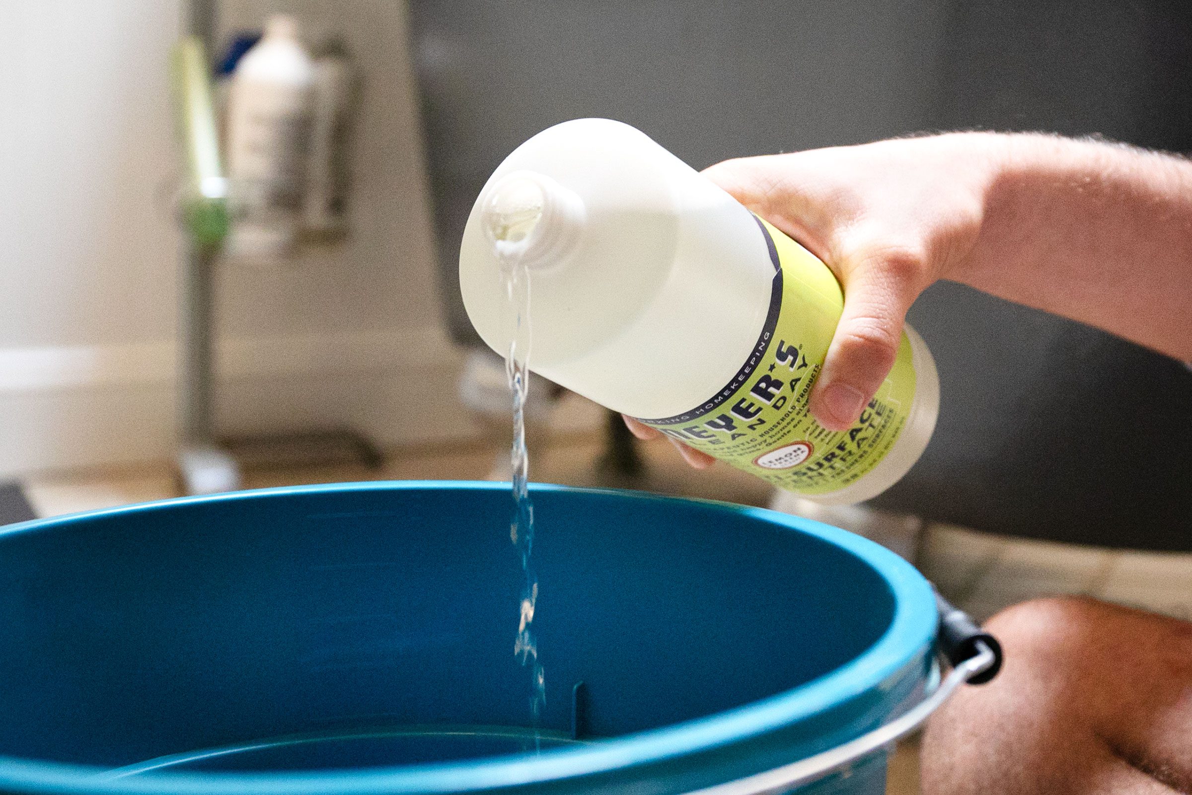 man pouring cleaning agent into bucket to prep for mopping