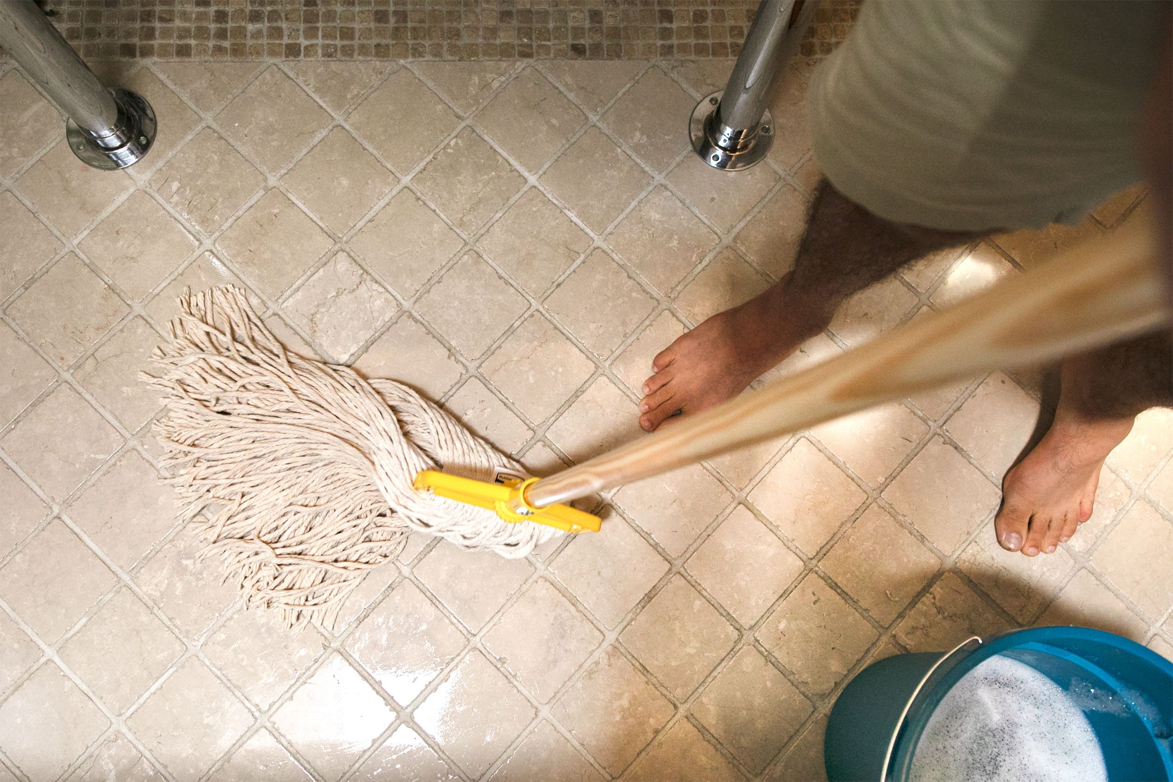 man moping bathroom floor in swishing motion