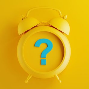 Yellow alarm clock displaying a large blue question mark, set against a bright yellow background.