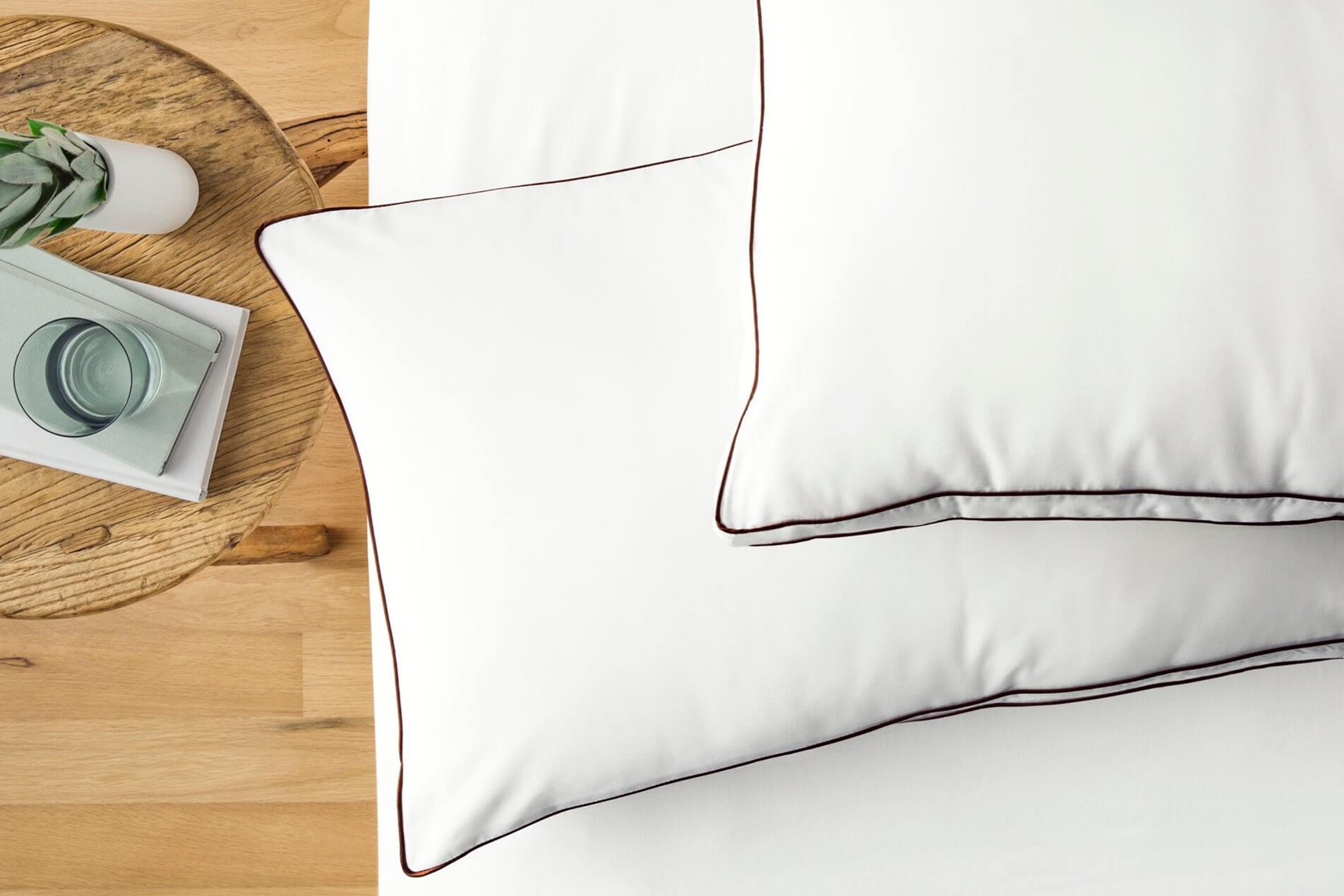 Saatva Latex Pillows on a bed next to a wood table