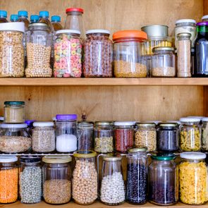 Jars store various dry foods, such as grains and spices, neatly arranged on wooden pantry shelves.