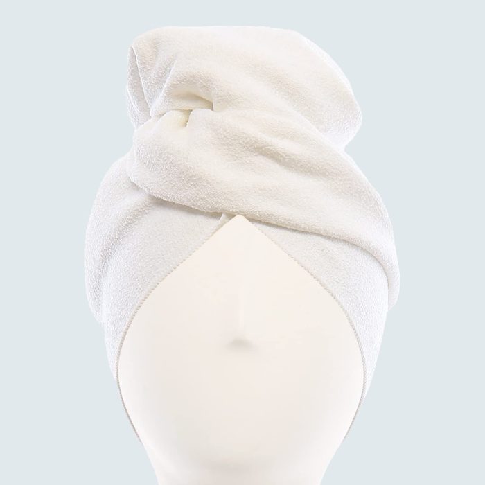 A white towel wraps around a mannequin's head, forming a turban shape, set against a plain light gray background.
