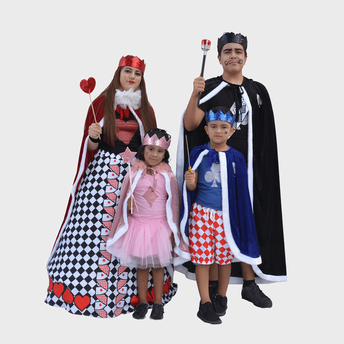 Four people wear royal-themed costumes, holding props, standing together in a neutral setting; two adults in card suits, two children in crowns and capes.