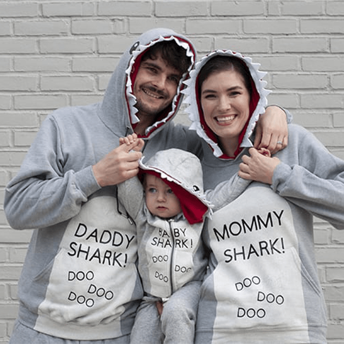 Family wears shark-themed hoodies reading 