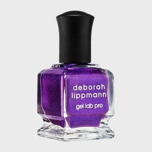 Purple nail polish bottle stands on a light surface, featuring the text 