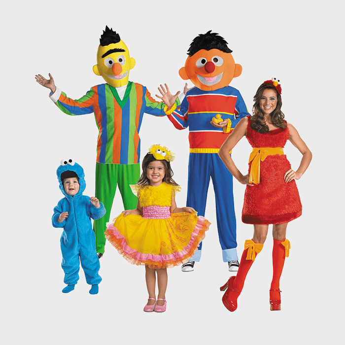 Adults and children wear colorful character costumes, standing together happily against a plain white background.