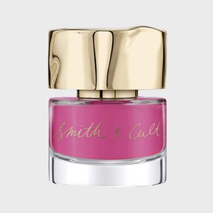 A pink nail polish bottle with gold cap displays gold script text 