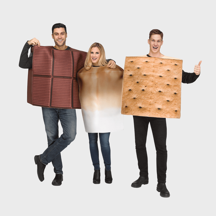 Three people wear chocolate, marshmallow, and graham cracker costumes, smiling and posing playfully against a plain background.