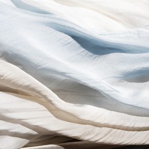 Flowing fabric drapes softly, creating gentle waves, in a serene, diffused light setting.