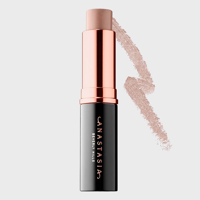 Makeup stick extends vertically, revealing beige shade, against a light background with beige swatch. Text: 