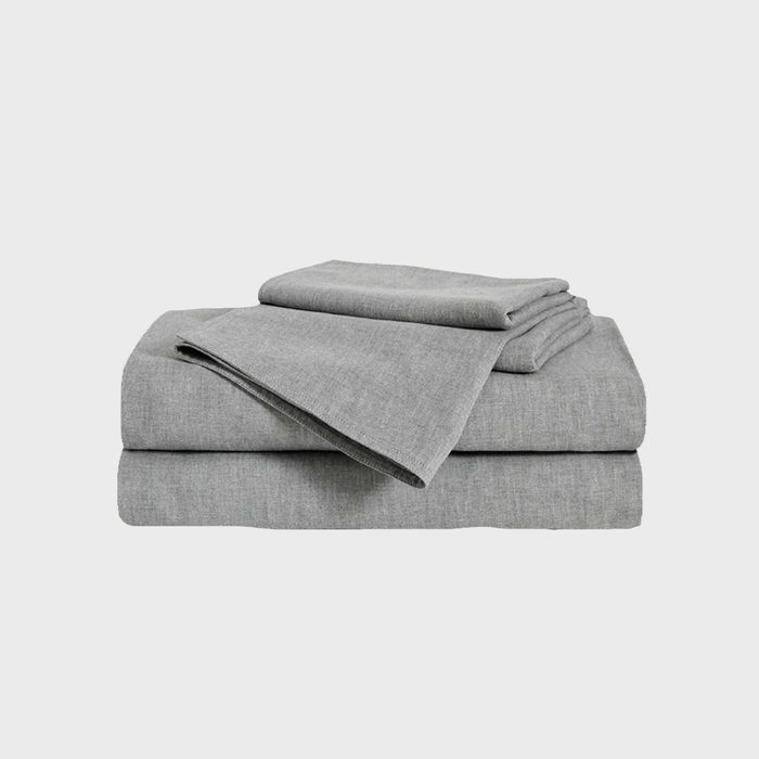 Gray folded bed sheets stacked neatly against a plain background.