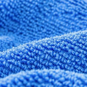 Blue fabric texture shows detailed woven fibers, creating a soft, wavy pattern. The material appears plush and densely packed.