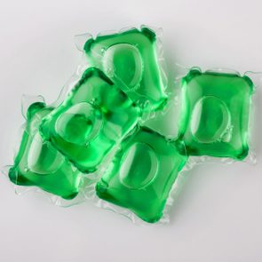 Green laundry detergent pods clustered together on a white surface.